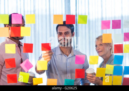 Business people looking at post it on the wall Stock Photo