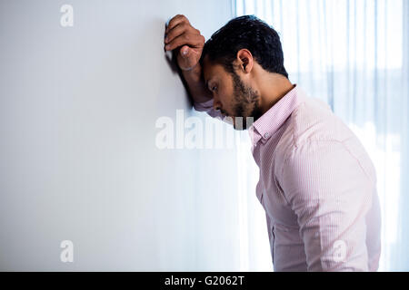Thoughtful young businessman standing against  wall Stock Photo