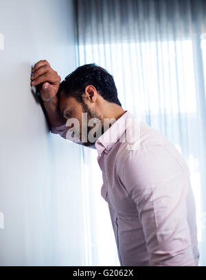 Side view of thoughtful young businessman standing against wall Stock Photo