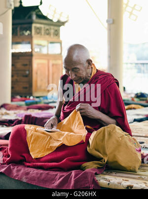 A Tibetan monk prays before a day of teachings by His Holiness the Dalai Lama at Tsuglagkhang, the Dalai Lama's temple in India. Stock Photo