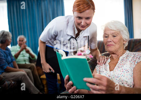 Senior woman reading book with nurse Stock Photo