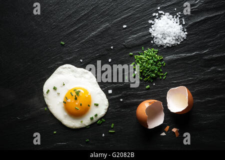 Fried egg on a slate with chives and coarse sea salt . Stock Photo