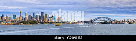 Sydney cityscape with landmarks , skyscrapers and Harbour bridge across harbour water on a sunny summer day. Marine traffic Stock Photo