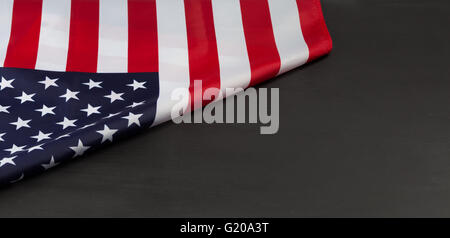 Folded American flag on black chalkboard with copy space Stock Photo