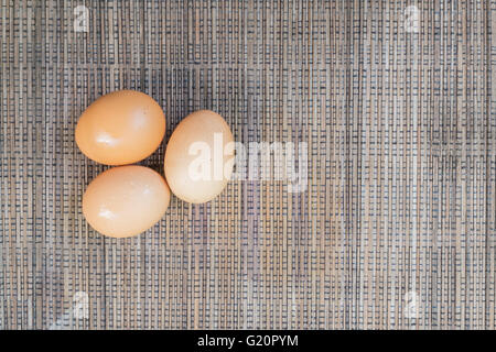 Three chicken egg lay on table cloth. Can be as background for farm, health, food, life, and nature. Stock Photo