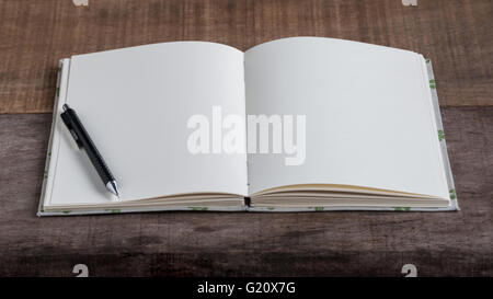 Closeup of opened handmade book and pencil on wooden background Stock Photo