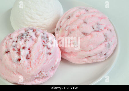 three  scoops of white and pink ice cream on white plate, close up, full frame, horizontal Stock Photo