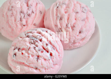three scoops of pink ice cream, strawberry or cherry flavor,  on white plate, close up, full frame Stock Photo