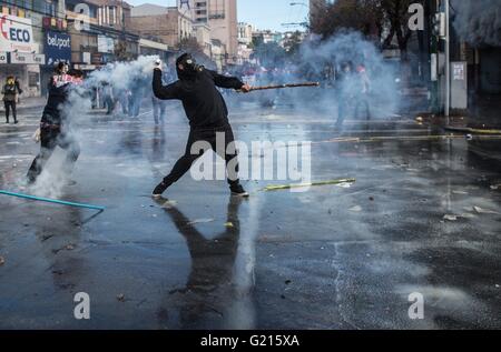 Valparaiso, Chile. 21st May, 2016. A demonstrator throws a tear gas canister back to riot police during a march called by the Confederation of Chilean Students (CONFECH), in Santiago, capital of Chile, on May 21, 2016. Demonstrators clash with riot police in the surroundings of the Congress in Valparaiso, Chile, while Chilean President Michelle Bachelet delivers her annual message to the nation. The massive march of students, workers and several social organizations in the country ended up with violent incidents, according to local press. Credit:  Jorge Villegas/Xinhua/Alamy Live News Stock Photo