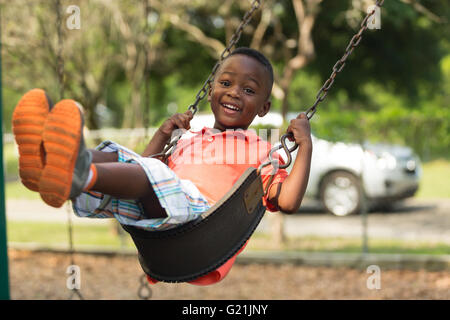 Small child swinging in the park smiling and having fun Stock Photo
