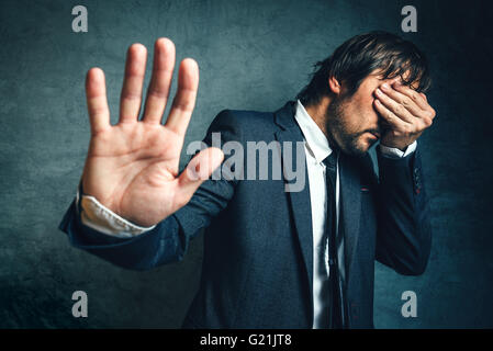 Stressed businessman after business project failure, covering eyes in despair and hand gesturing stop to camera. Stock Photo