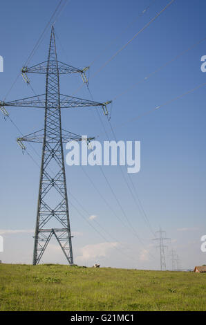 Electricity transmission pylon silhouetted against blue sky at dusk Stock Photo