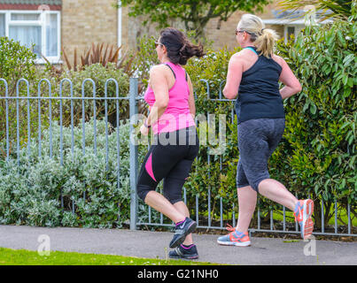 Pair of female joggers on a residential street in the UK. Stock Photo