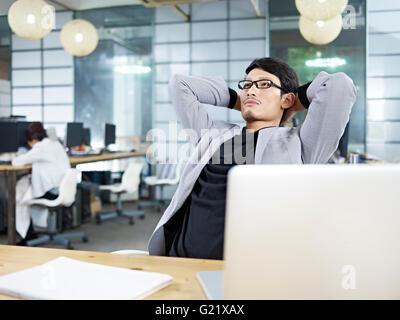 young asian business executive leaning back in a chair and thinking. Stock Photo