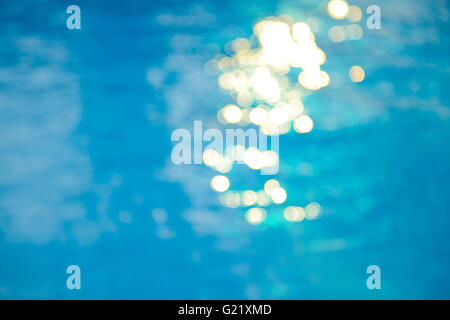Soft focus bokeh light effects over a rippled, blue water background in the pool. Stock Photo