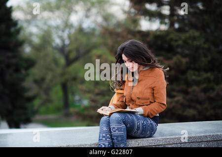 Young adult handsome man sitting at cafe or street restaurant and smiling Stock Photo