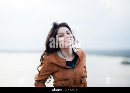 Positive young man alone behind table in summer cafe smiling looking sideways Stock Photo