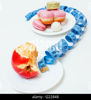 new diet concept, question sign in shape of measurment tape between red apple and donut isolated on white Stock Photo