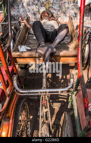 Man sleeping on his bicycle truck in Delhi, India Stock Photo