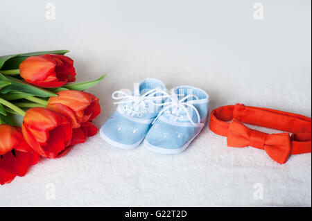 red tulips tie and children blue boots on  white background Stock Photo