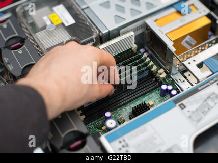 Computer technician installing RAM memory into motherboard. Stock Photo