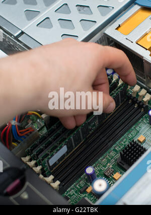 Close-up of a person installing RAM into a computer motherboard. The ...