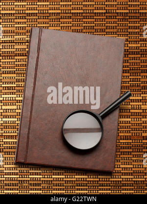 Notepad and magnifying glass on rod background Stock Photo