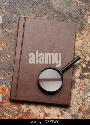 Notepad and magnifying glass on rusty background Stock Photo
