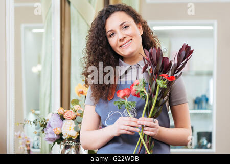 Portrait of beautiful curly woman florist standing in flower shop Stock Photo