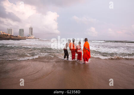 Colombo, Sri Lanka,   23rd May, 2016. Young novice monks and others play in the sea at sunset at Galle Face Green. It is a public holiday, and day three  of Vesak celebrations, which commemorates the birth of Buddha, his attaining enlightenment and his passing away on the full moon day of May which fell this year on May 21. Colombo, Sri Lanka. Stock Photo