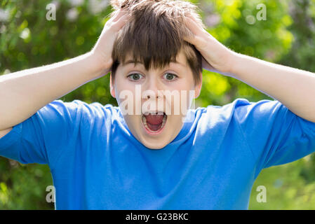Teen boy screaming and holding hands behind his head Stock Photo