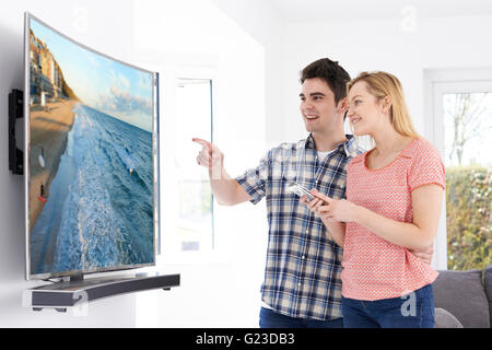 Young Couple With New Curved Screen Television At Home Stock Photo