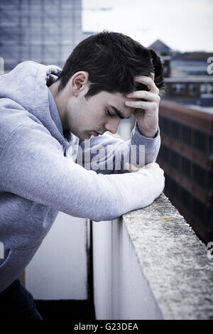 Depressed Young Man Contemplating Suicide On Top Of Tall Building Stock Photo