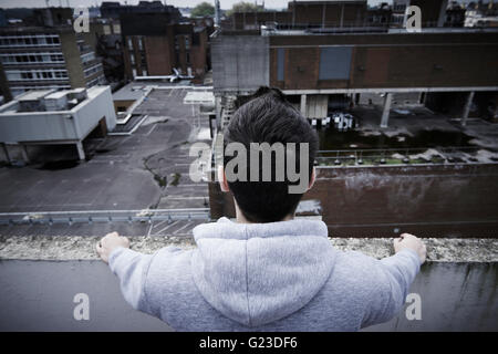 Depressed Young Man Contemplating Suicide On Top Of Tall Building Stock Photo