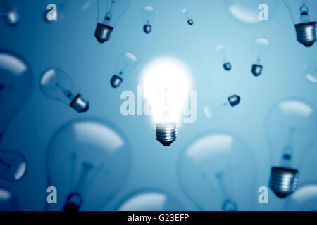 Many bulbs on a blue background and one of them is glowing. Stock Photo