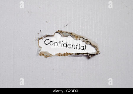 The word confidential appearing behind torn paper. Stock Photo