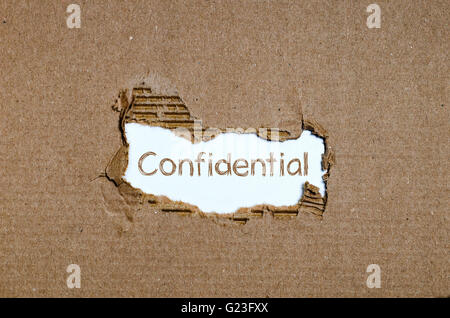 The word Confidential appearing behind torn paper. Stock Photo