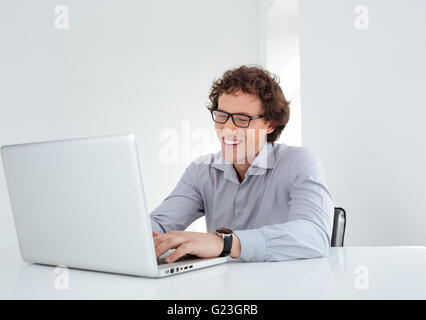 Laughing businessman working on laptop computer in office Stock Photo