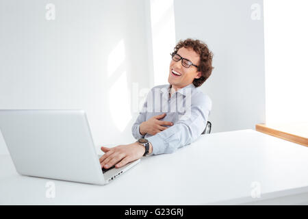 Laughing businessman sitting at his workplace in office Stock Photo