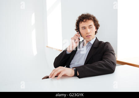 Pensive businessman talking on the phone in office Stock Photo