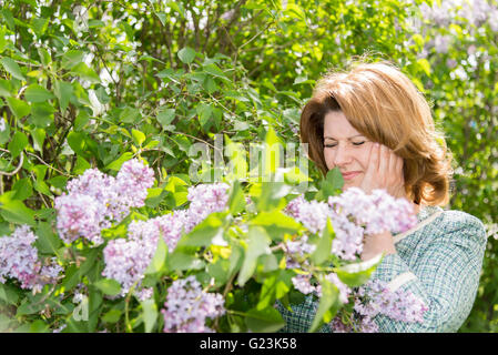 Woman suffering from migraine about blooming lilac Stock Photo