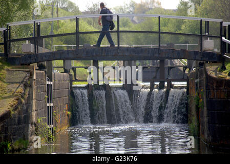 Man crossing a lock bridge on the Forth and Clyde canal, Glasgow, Scotland, UK. Stock Photo