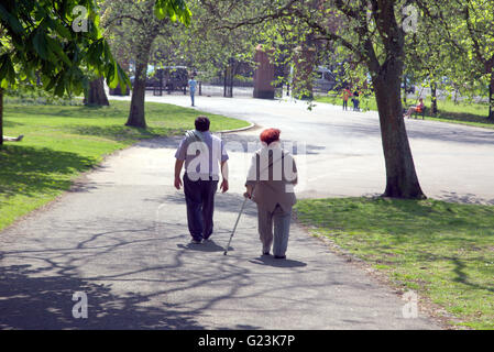 Middle aged or old couple with walking stick walking in Kelvingrove Park Glasgow, Scotland, UK. Stock Photo