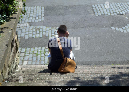 young man  or boy sitting on steps viewed from above,Glasgow, Scotland, UK Stock Photo