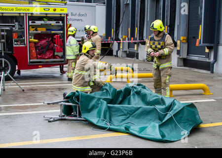 Fire fighters constructing a a dam using a salvage sheet and triple extension ladder. Stock Photo