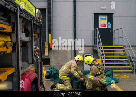 Fire fighters constructing a a dam using a salvage sheet and triple extension ladder. Stock Photo