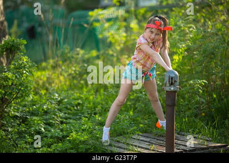 Little girl near the water pump in the village. Stock Photo