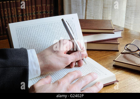 man with pen in hand looking for references in a book Stock Photo