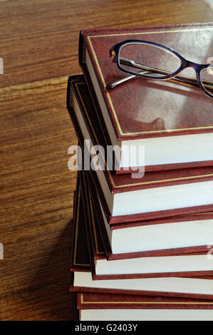stack of books and glasses on tablel horizontal image and window lighting Stock Photo