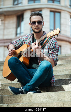 Casual young man playing on the guitar outdoors Stock Photo